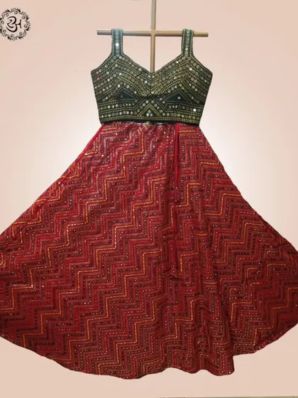 The full flare of the red chevron-patterned lehenga skirt is displayed here. The intricate mirror work on the green blouse adds a touch of sparkle, ideal for festive nights.