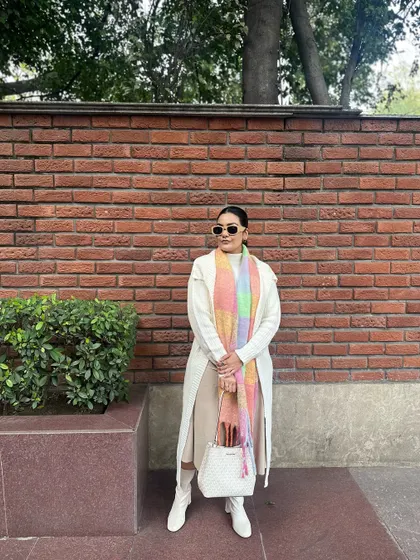 The texture of the woven bag complements the soft knits of the sweater and scarf.