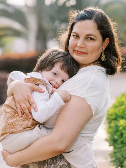 A mother holding her son, who is giving a sweet, shy smile. A tender and authentic moment.