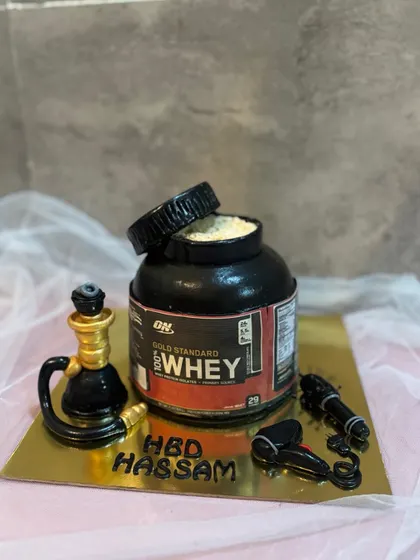 A full view of the sculpted whey protein tub cake, complete with a mini hookah and hairdryer, capturing all of the birthday boy's favorite things.