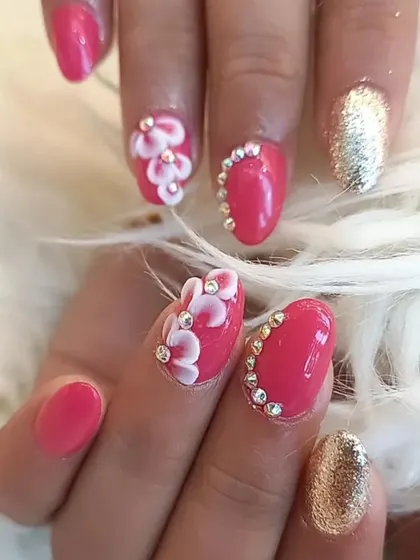 A detailed view of the pink and gold 3D floral manicure. The placement of rhinestones around the cuticle and on the flowers adds a luxurious touch.