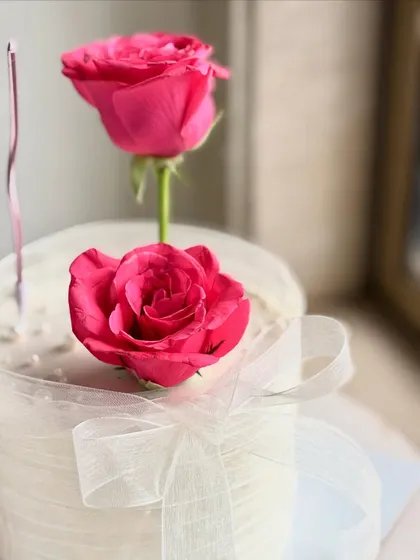 A close-up on the fresh pink roses and the delicate sheer ribbon, showcasing a soft and romantic aesthetic that's perfect for any celebration.