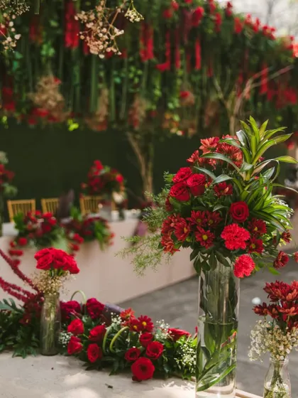 A cascade of crimson blooms and varied textures in this tablescape decor. The layering of different red flowers and greenery adds depth and visual interest.