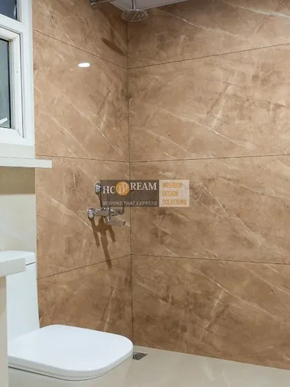 Another bathroom from the same project, showcasing a different style with a clean white vanity and beautiful brown wall tiles.