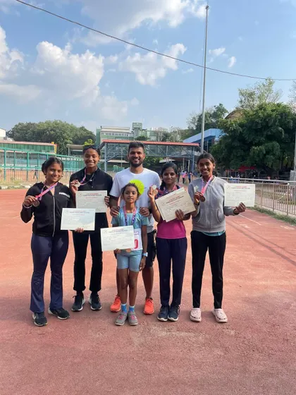 A successful day at the Summer Athletic Meet. Our coach stands with a group of our young female athletes, all proudly displaying their medals and certificates.