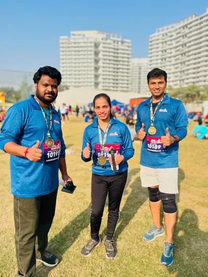 Three happy finishers with their medals, giving a thumbs up to a great race day experience.