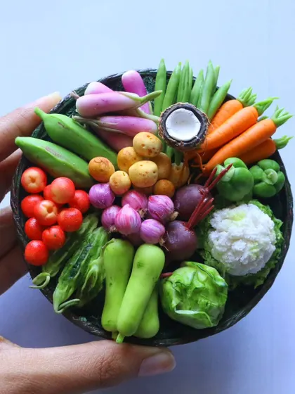 A hand holding a basket of hyper-realistic miniature vegetables, a testament to the skills taught in my course.