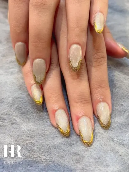 The epitome of chic. This sophisticated design features a neutral, creamy base with a stunning, textured gold leaf effect framing the tips of the nails for a touch of understated luxury.