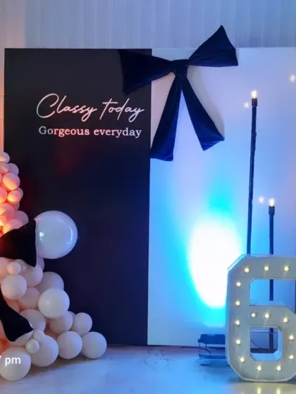 A classy black and white theme for a 60th birthday. The backdrop features a personalized quote, accented with bows, balloons, and large marquee numbers.