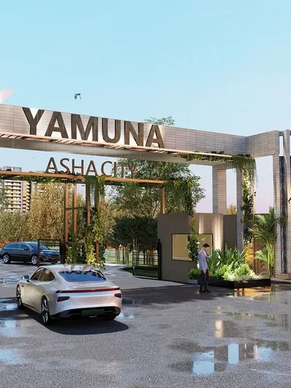 The grand entrance gate for the Yamuna Asha City development. The design uses clean lines, integrated planters with climbing greenery, and prominent branding to create a modern and inviting gateway that sets a premium tone for the entire community.
