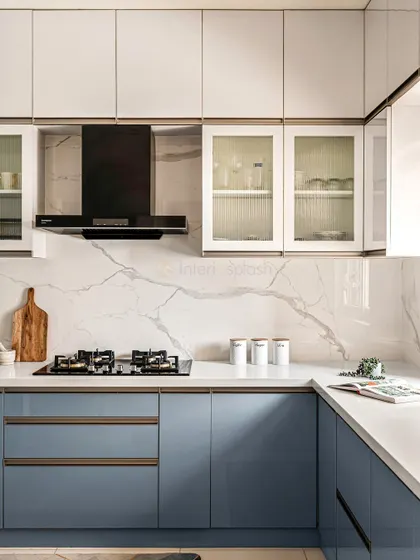 This shot highlights the clean lines and materials used, including the glossy blue cabinets, white countertops, and elegant marble-look backsplash.