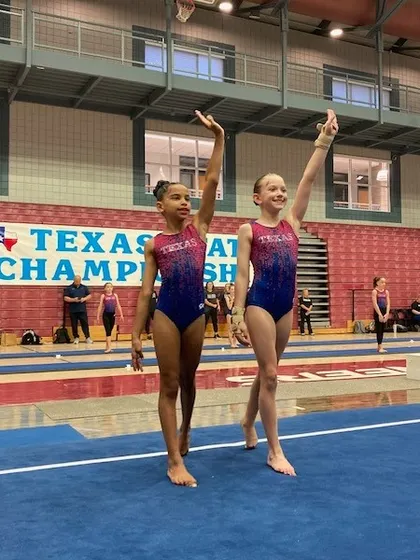 Two Level 6 teammates walk out onto the floor together at the Texas State Championships.
