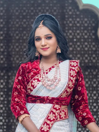 A beautiful red and white designer saree-lehenga, paired with a multi-layered pearl necklace. This is a unique and fashionable choice for a modern bride.