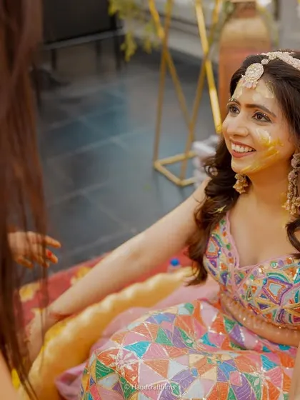 A close-up of the bride during her Haldi, smiling and enjoying the moment. The makeup is minimal and fresh, perfect for this messy and fun event.