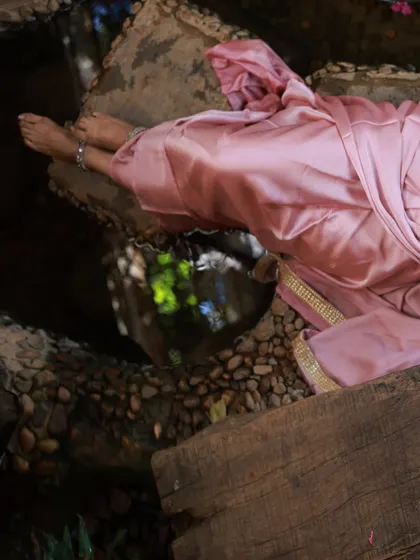 An abstract shot focusing on the model's feet and the pink saree, with a reflection in the water. This adds an artistic and serene element to the series.