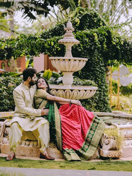 A regal and romantic pose by a garden fountain, with the couple dressed in colorful and elegant traditional Indian attire.