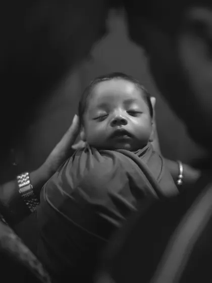 A creative black and white shot focusing on a sleeping newborn being held securely in their parents' hands.