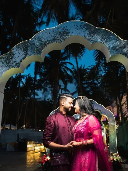 A romantic portrait of the couple under a shimmering mosaic arch. This unique decor piece caught the twilight beautifully, creating a magical photo spot at their Sangeet.