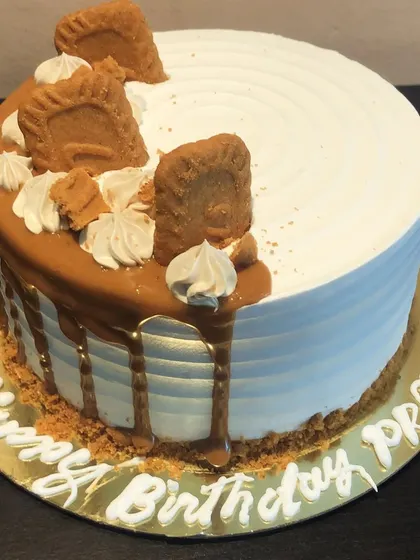 A stunning eggless Lotus Biscoff birthday cake. This design features a smooth white frosting, a Biscoff drip, and is topped with crumbled and whole Biscoff cookies.