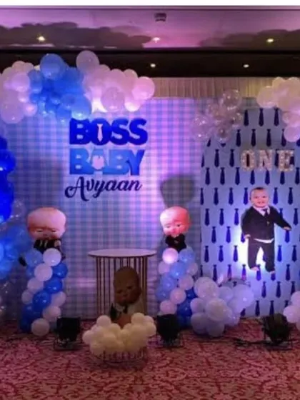 A fun Boss Baby theme for Avyaan's first birthday. This setup features character cutouts, a themed backdrop with a "ONE" graphic, and balloon decorations in shades of blue and white.