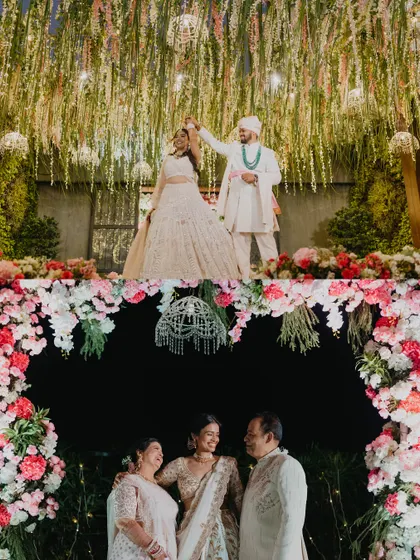 Our decor is designed to be the perfect frame for your most cherished moments. Here, the couple shares their first dance under a canopy of hanging greens, while another photo captures a sweet family moment against a floral arch.