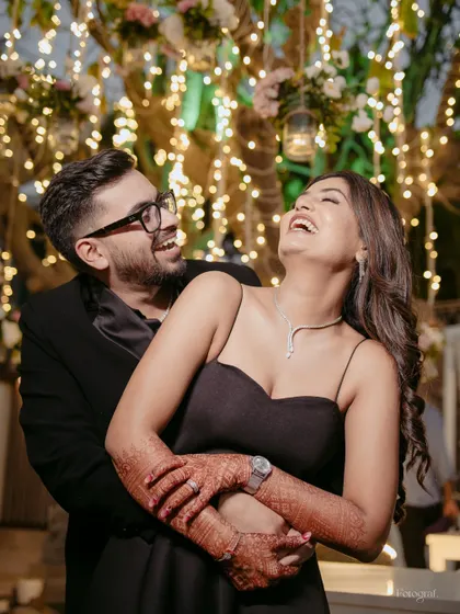Pure, unadulterated laughter. This candid shot captures the couple's joyful interaction against a backdrop of fairy lights, their happiness is infectious.