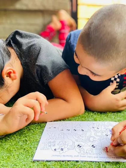A candid moment of two kids completely absorbed in coloring a page from the Doodle Book.