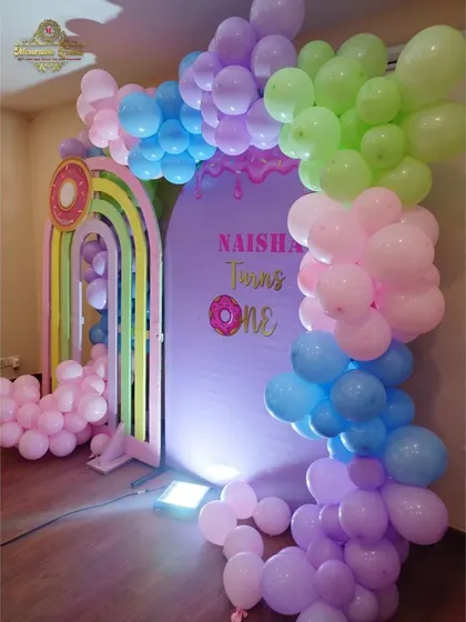 A close-up of the 'Candyland' theme, showing the colorful balloon garland and rainbow arch details.