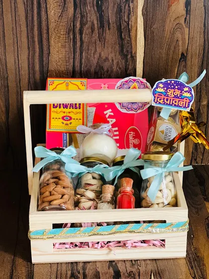 A rustic wooden crate hamper for Diwali, filled with jars of dry fruits, Ferrero Rocher chocolates, and festive stickers.