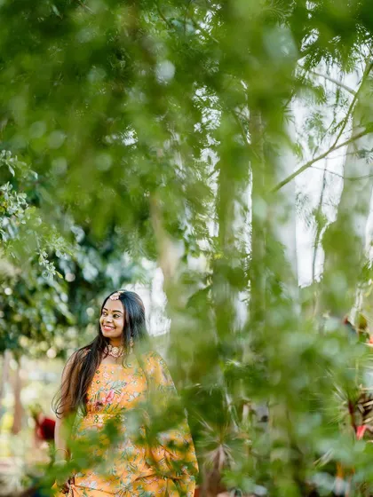 A serene portrait of a bride-to-be amidst lush greenery during her Haldi celebrations.