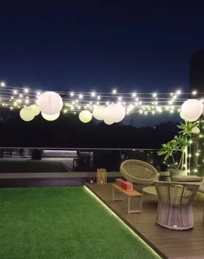 Another view of the terrace lighting setup, showing how the combination of string lights and paper lanterns can transform an outdoor space for a special occasion.