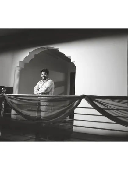 The same portrait in black and white, giving it a timeless and classic feel. This shot highlights the architecture and the groom's confident pose.