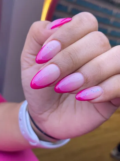 A vibrant pink ombre or "aura" nail design with a subtle sprinkle of glitter. This style is trendy, fun, and perfect for adding a pop of color.