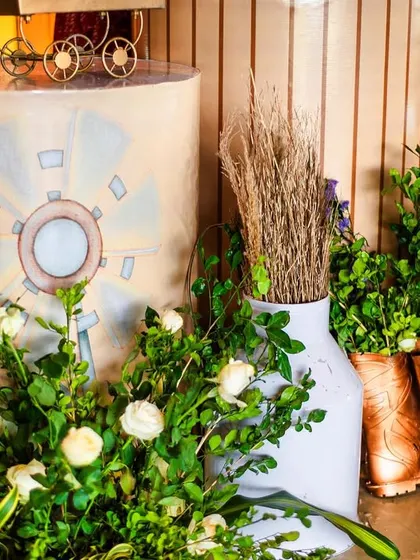 A close-up of the rustic details, including flowers arranged in painted rain boots and milk cans. These creative touches add authenticity and charm to the farm theme.