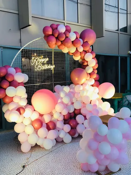 A gorgeous balloon arrangement in shades of pink and white, with a neon sign and a mesh grid backdrop, creating a soft and romantic vibe.