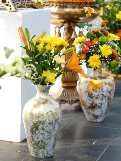 An assortment of flowers in distressed-finish golden vases, adding a touch of vintage charm to the Haldi decor.