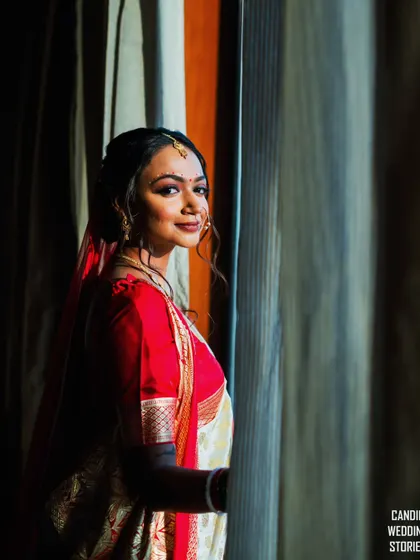A stunning portrait of the bride by the window, with beautiful natural light highlighting her features and traditional attire.