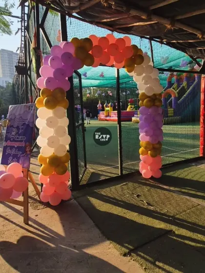 A simple yet elegant balloon arch in princess colors of pink, purple, and gold, marking the entrance to the party area.