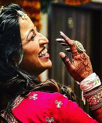 A smile is the best accessory for a bride. This candid photo captures a bride's pure happiness, with her detailed mehndi beautifully accenting her hand as she laughs.