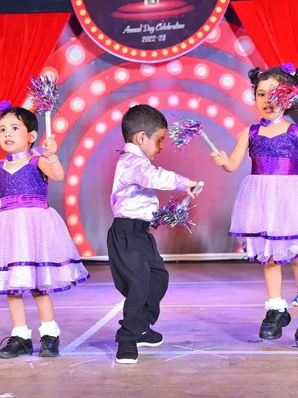 A dynamic action shot of the children dancing in their purple and lilac dresses, showing how the costumes allow for easy movement.