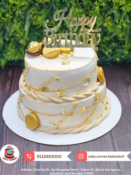 An elegant two-tier white and gold cake, adorned with macarons and Ferrero Rocher chocolates. This is a sophisticated choice for a stylish birthday celebration.