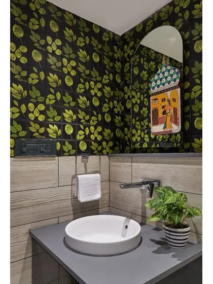 The powder bathroom in the "Blue" apartment features a dramatic, leafy wallpaper, creating a jewel-box effect in a small space.