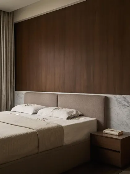 A serene view of the master bed, set against a backdrop of rich wood paneling and a low Carrara marble wainscot. The material palette is intentionally limited to create a calming, cohesive atmosphere.