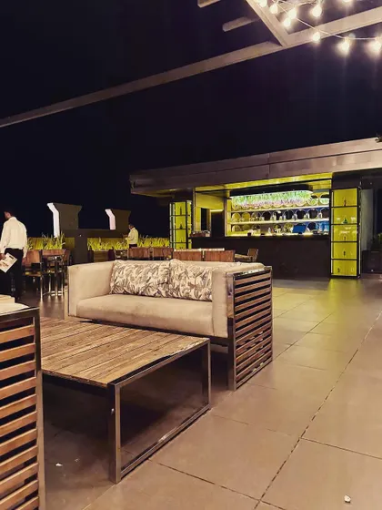 A comfortable lounge sofa with patterned cushions, offering a relaxed seating option with a direct view of the bustling bar area.