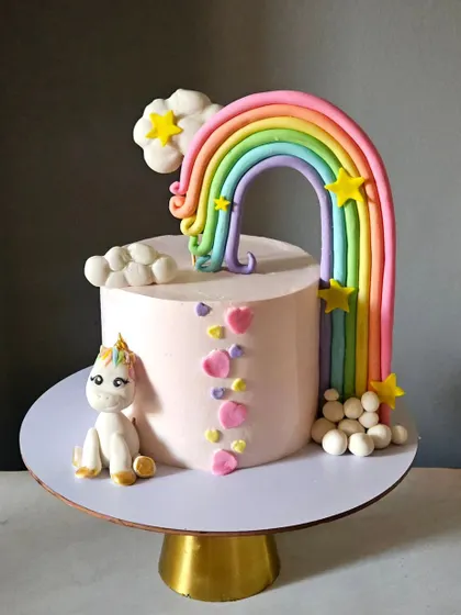 A simple yet magical unicorn and rainbow cake. This design features a single unicorn figurine with a large, cascading rainbow made of fondant, perfect for a whimsical celebration.