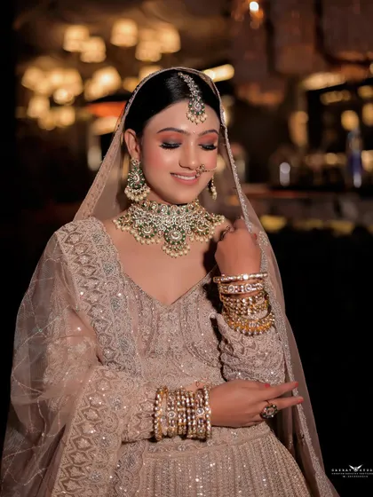 A graceful portrait of the bride looking down at her hands. This pose highlights her beautiful bangles and the intricate details of her outfit's sleeves and dupatta.