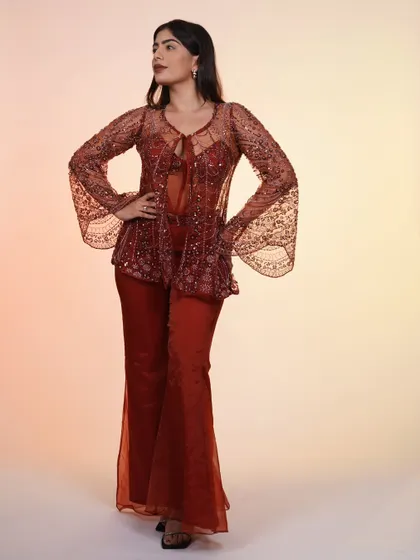 A full-length shot of the rust-colored Indo-western set. The flared pants and bell sleeves on the jacket create a beautiful, cohesive silhouette.