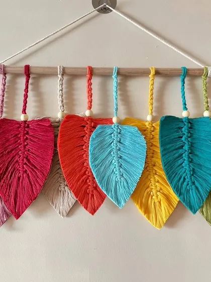 A rainbow of leaves! This cheerful wall hanging features seven leaves in seven different bright colors, perfect for adding a playful and vibrant touch to your home.
