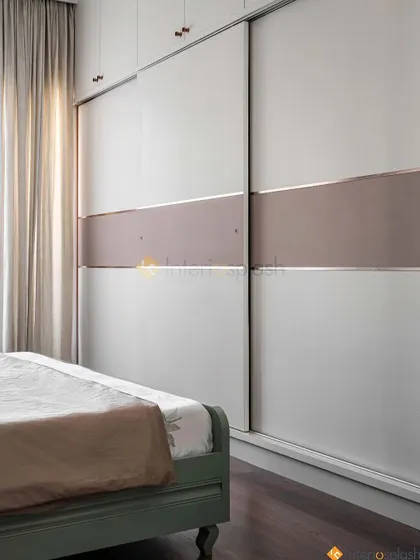 This bedroom features a large sliding wardrobe with a simple two-tone design. The space-saving doors are ideal for rooms where a swing door might not be practical.