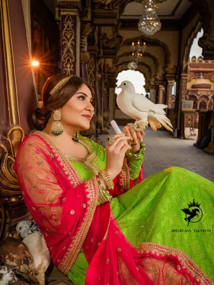A whimsical shot from our creative photoshoot, featuring a model in our green and pink lehenga holding a white dove. We can help you plan and execute unique concepts for your photos.